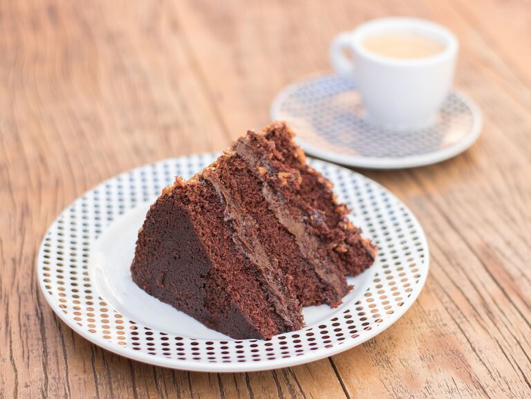 Delicious slice of chocolate cake served with coffee on a rustic wooden table, perfect for dessert lovers.